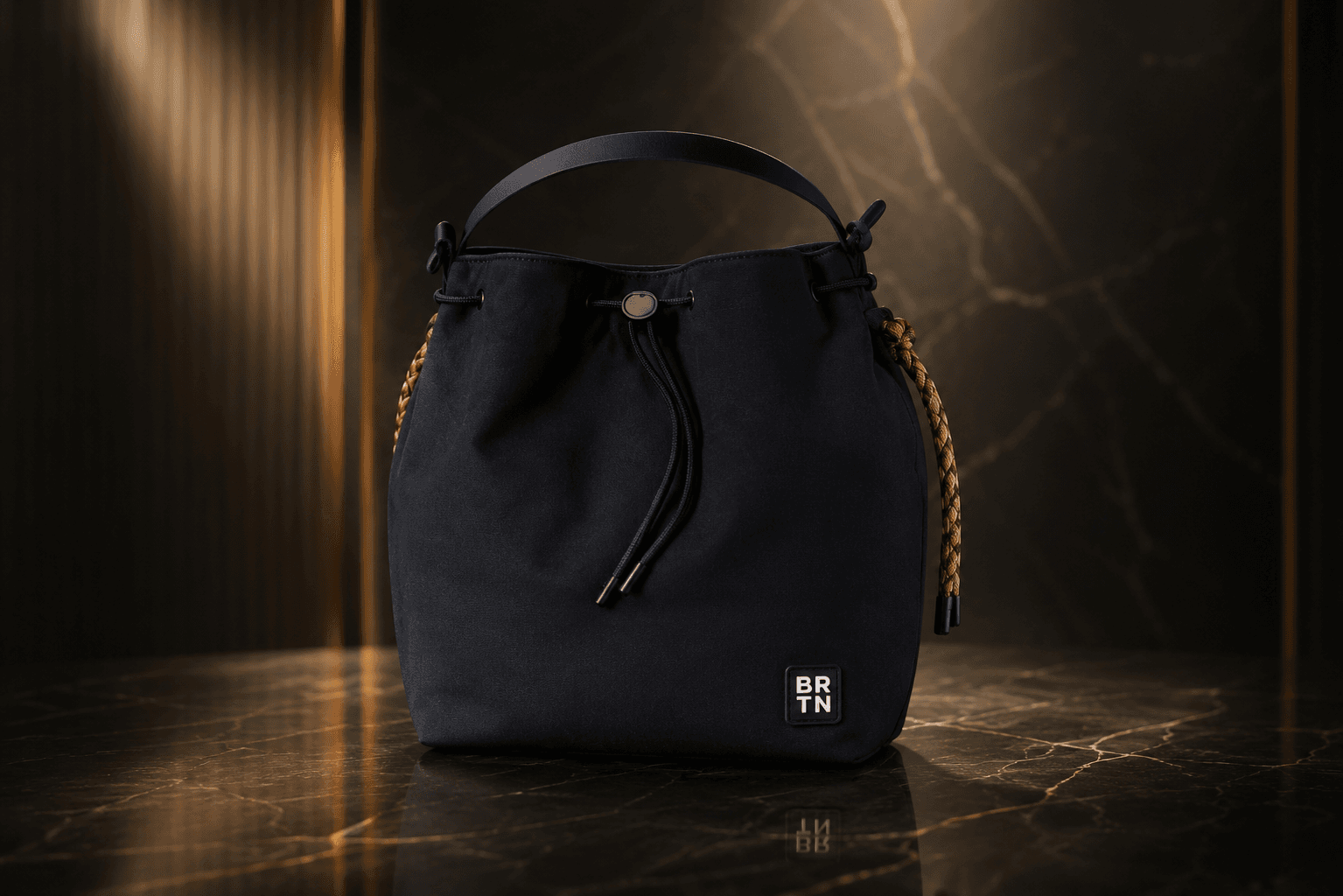 Brighton black bucket bag lit against a dark marble and gold studio backdrop